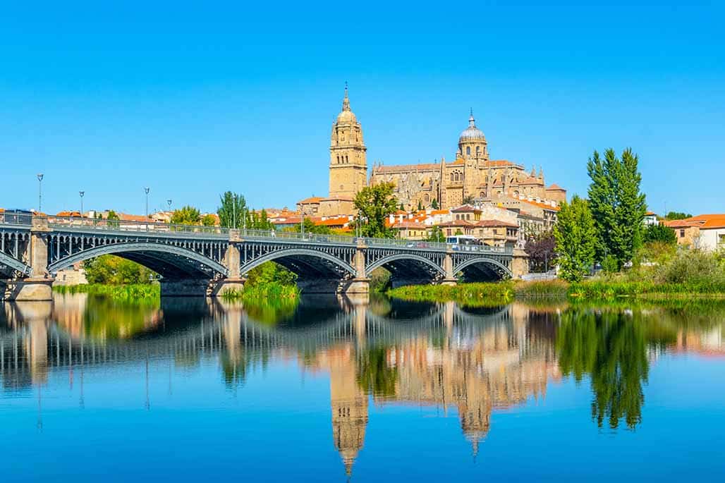 Salamanca Cathedral viewed behind bridge of enrique esteven on river Tormes, Spain.