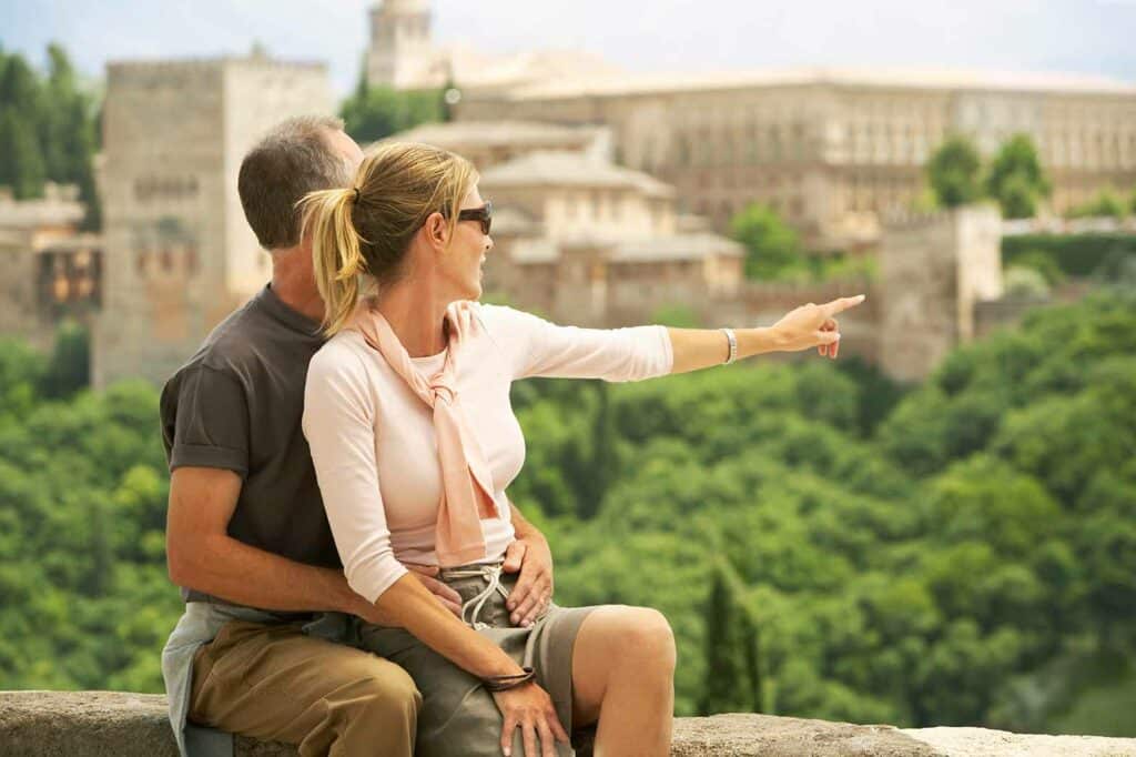 couple sitting on wall with woman pointing at the Alhambra in Granada