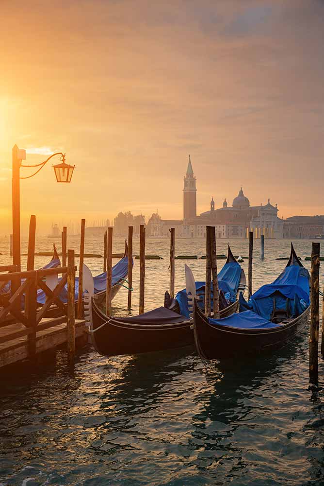 Gondolas by Saint Mark square during sunrise with San Giorgio di Maggiore church in the background in Venice Italy